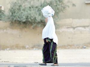 مسنة فلسطينية تحمل مشتريات فوق رأسها