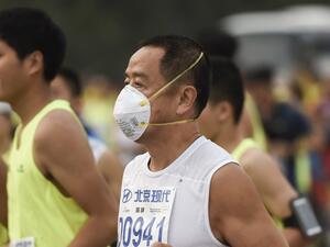 A runner wears a face mask as he takes part in the 35th Beijing International Marathon in Beijing on September 20, 2015, with the 42-kilometer course beginning at Tiananmen Square and ending at the Olympic Park. Some participants wore face masks to protect themselves from air pollution. AFP PHOTO / FRED DUFOUR (Photo by FRED DUFOUR / AFP)