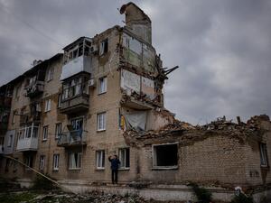 رجل يلتقط صورة سلفي أمام مبنى مهدم في دونيتسك