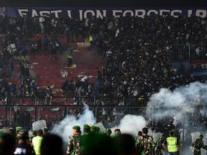 This picture taken on October 1, 2022 shows security personnel (lower) on the pitch after a football match between Arema FC and Persebaya Surabaya at Kanjuruhan stadium in Malang, East Java. At least 127 people died at a football stadium in Indonesia late on October 1 when fans invaded the pitch and police responded with tear gas, triggering a stampede, officials said. (Photo by AFP)