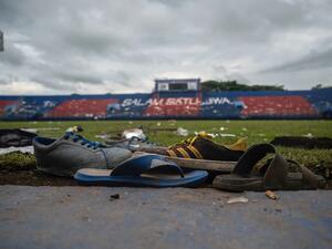 Discarded shoes sit by the pitch at Kanjuruhan stadium days after a deadly stampede following a football match in Malang, East Java on October 3, 2022. Anger against police mounted in Indonesia on October 3 after at least 125 people were killed in one of the deadliest disasters in the history of football, when officers fired tear gas in a packed stadium, triggering a stampede. (Photo by Juni Kriswanto / AFP)