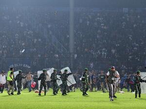 This picture taken on October 1, 2022 shows members of the Indonesian army securing the pitch after a football match between Arema FC and Persebaya Surabaya at Kanjuruhan stadium in Malang, East Java. At least 127 people died at a football stadium in Indonesia late on October 1 when fans invaded the pitch and police responded with tear gas, triggering a stampede, officials said. (Photo by AFP)