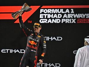 Red Bull's Dutch driver Max Verstappen raises the winner's trophy on the podium after the Abu Dhabi Formula One Grand Prix at the Yas Marina Circuit in the Emirati city of Abu Dhabi on November 20, 2022. (Photo by Ben Stansall / AFP)