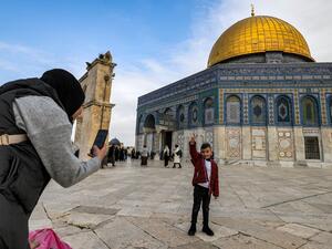 امرأة تلتقط صورة لطفل يقف أمام قبة الصخرة المشرفة