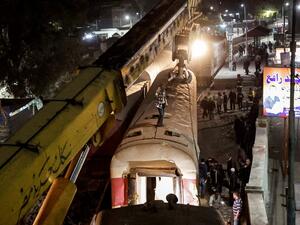 A crane is deployed to lift a derailed train at the scene of a railroad accident in the city of Qalyub in Qalyub province