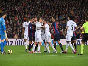 Spanish referee Ricardo De Burgos Bengoetxea shows a yellow card as players argue during the Spanish league football match between FC Barcelona and Real Madrid CF at the Camp Nou stadium in Barcelona on March 19, 2023. (Photo by LLUIS GENE / AFP)