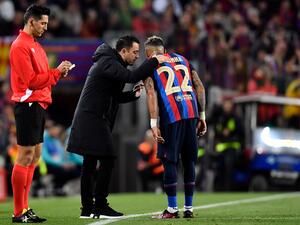 Barcelona's Spanish coach Xavi (C) talks to Barcelona's Brazilian forward Raphinha during the Copa del Rey (King's Cup) semi-final second leg football match between FC Barcelona and Real Madrid CF at the Camp Nou stadium in Barcelona on April 5, 2023. (Photo by Pau BARRENA / AFP)