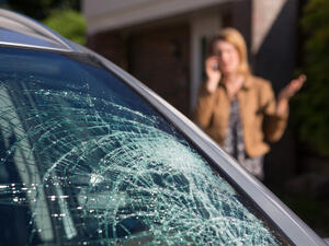 Woman Phoning For Help After Car Windshield Has Broken