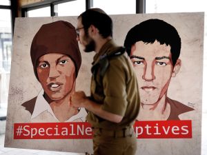 جندي اسرائيلي يمر من امام لوحة رسم عليها صورتا هشام السيد وأفراهام منغيستو المحتجزين لدى حماس