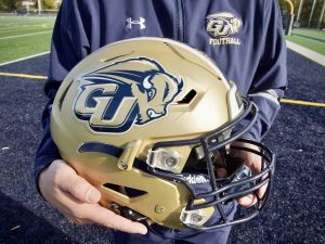 Chuck Goldstein, head football coach at Gallaudet University, holds a 5G-connected football helmet designed for deaf and hard of hearing players (Photo by Agnes BUN / AFP) American football