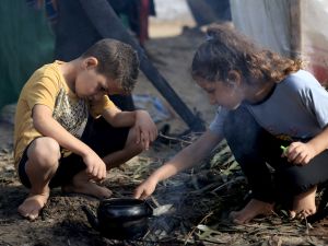 Internally displaced Palestinian children, who fled from the Israeli bombardment of the northern Gaza Strip and are now living in make shift shelters, light a fire to boil a kettle after overnight rainstorms in Khan Yunis, in the southern Gaza Strip on November 15 , 2023. (Photo by MAHMUD HAMS / AFP) Gaza