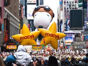 Snoopy balloon floats in the air during the annual Macy's Thanksgiving Day parade along Avenue of Americas with the Radio Music Hall in the background. (Gary 718/ Shutterstock)
