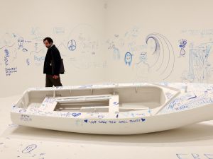 A visitor looks at an interactive artwork entitled 'Add Colour (Refugee Boat)', by Yoko Ono, during a photocall to promote the forthcoming exhibition 'Yoko Ono: Music of the Mind' (Photo by Daniel LEAL / AFP) Yoko Ono