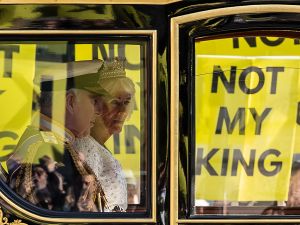 Britain's King Charles III and Britain's Queen Camilla travel in the Diamond Jubilee State Coach past protesters holding "Not My King" placards, from the anti-monarchy group Republic as they demonstrate ahead of the State Opening of Parliament. (Photo by HENRY NICHOLLS / AFP) King Charles