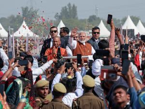 India's Prime Minister Narendra Modi (C) and Yogi Adityanath (C, left), Chief Minister of Uttar Pradesh, greet the supporters as they arrive to inaugurate the Amul Banas Dairy Plant, on the outskirts of Varanasi on February 23, 2024. (Photo by Niharika KULKARNI / AFP) India