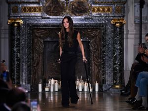 Victoria Beckham kisses David Beckham as she takes final bow on crutches — and shrugs off PETA protesters at her Paris show. (Julien De Rosa/ AFP)
