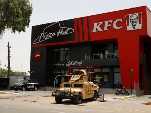 Iraqi security forces vehicles are stationed in front of a Kentucky Fried Chicken (KFC) and Pizza Hut fast food restaurants in the Al-Jadriya neighbourhood in Baghdad on May 30, 2024. (Photo by AHMAD AL-RUBAYE / AFP)