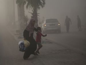 امرأة فلسطينية مع طفلها، وسط الدخان عقب غارة اسرائيلية على مخيم النصيرات