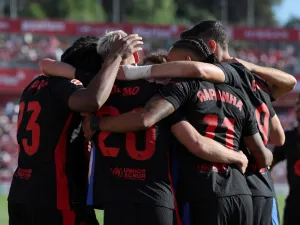 Barcelona's Spanish forward #20 Daniel Olmo celebrates with teammates scoring his team's third goal during the Spanish league football match between Girona FC and FC Barcelona at the Montilivi stadium in Girona on September 15, 2024. (Photo by LLUIS GENE / AFP)
