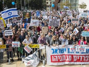 Israeli protesters raise signs as they demonstrate against Prime Minister Benjamin Netanyahu in the wake of police recommendations to indict corruption, in the coastal city of Tel Aviv on Feb. 16, 2018. 
(JACK GUEZ / AFP)