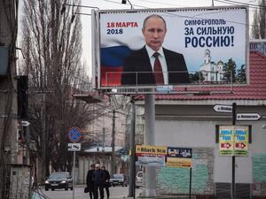Peole walk past campaign billboards of Russian President Vladimir Putin, reading "Simferopol for the Strong Russia! Vladir Putin" in Simferopol on Mar. 9, 2018. Russians will vote Mar. 18 during presidential election that Vladimir Putin is almost guaranteed to win.
(STRINGER / AFP)