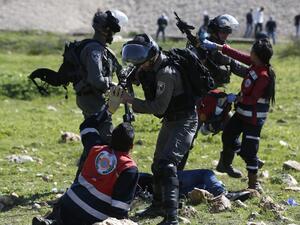 Palestinian Civil Defense volunteers scuffle on Mar. 12, 2018 in the West Bank town of Birzeit, near Ramallah, with Israeli soldiers as they attempt to give aid to an injured Palestinian demonstrator during a protest by students of the Birzeit University against the arrest of the the head of Palestinian student council by an Israeli undercover commando. (ABBAS MOMANI / AFP)