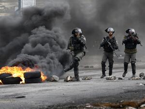 Israeli border guards walk through fumes from burning tires during clashes with Palestinian protesters near the Israeli settlement of Beit El in the Israeli occupied West Bank, on Mar. 30, 2018, after Land Day demonstrations. Land Day marks the killing of six Arab Israelis during 1976 demonstrations against Israeli confiscations of Arab land.
(ABBAS MOMANI / AFP)