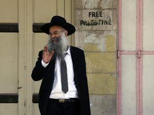 An Israeli settler walks passed Palestinian shops, closed by Israeli soldiers during the settlers' visit, in the occupied West Bank city of Hebron on Mar. 2, 2018, as he makes his way to visit the tomb of Othniel Ben Kenaz. 
(HAZEM BADER / AFP)