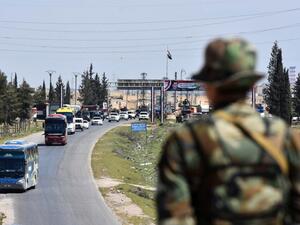 A convoy transporting Jaish al-Islam fighters and their families from the former bastion's main town of Douma arrives at the entrance to the northern Syrian city of Aleppo after being evacuated from the last rebel-held pocket in Eastern Ghouta on Apr. 3, 2018. 
(George OURFALIAN / AFP)