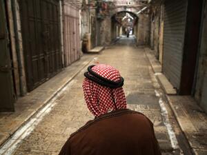 A Palestinian man walks past closed shops on an empty street in the Israeli occupied West Bank city of Nablus on May 15, 2018, during a general strike called for by leaders in solidarity with Gaza and in protest against the US embassy's move to Jerusalem. (Jaafar ASHTIYEH / AFP)