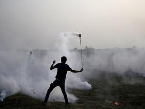 A Palestinian protester uses a slingshot in the smoke billowing from tear gas shot by Isreali forces during a demonstration along the border between Israel and the Gaza strip, east of Gaza City, on May 25, 2018. (MOHAMMED ABED / AFP)