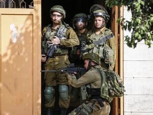Israeli soldiers stand through a doorway as another takes aim outside during clashes with Palestinians (AFP)