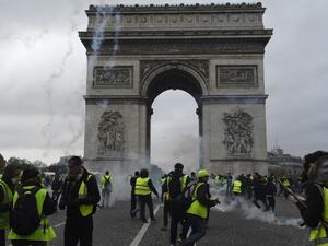 Protestors of the yellow vest (gilet jaune) movement walk past the Arc of Triomphe on the Champs Elysees in Paris, on November 24, 2018 during a protest against rising oil prices and living costs. (AFP)
