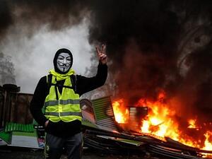 A protester wearing a Guy Fawkes mask makes the 'Victory' sign during a protest of the Yellow Vests against rising oil prices and living costs, on December 1, 2018, in Paris. (AFP)