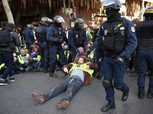 An activist of "Les amis de la terre" (Friends of the Earth) environmental NGO is evacuated by riot police during a demonstration outside the headquarters of French banking group Societe general to denounce its alleged support of fossil fuel inudstries 8 in Paris (AFP)