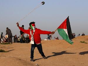 A young Palestinian protester, wearing a Guy Fawkes mask painted in the colours of the Palestinian flag and holding a Palestinian flag in his hand, uses a slingshot to hurl objects during clashes in Gaza . (AFP)
