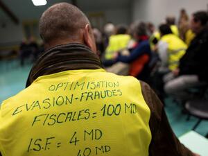 A man wearing a yellow vest with a slogan reading in French "Optimisation, tax avoidance = 100 billions, ISF = 4 billions) attends a meeting called by local members of the "yellow vest" (Gilets Jaunes) movement. (AFP)