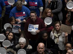 A federal worker stands with a placard reading "Will Work For Pay" as other federal employees stage a rally to call for a vote on the shutdown. (AFP/ File)