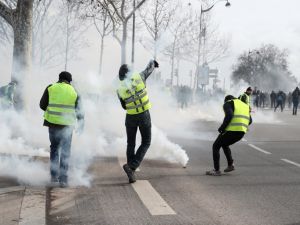 Protesters wearing a yellow vest throw back tear gas canisters to police officers near the National Assembly in Paris, on February 9, 2019. (AFP/ File)