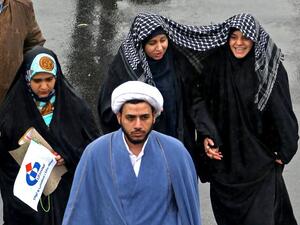 Iranian women march together in the rain under a shared scarf during a ceremony celebrating the 40th anniversary of Islamic Revolution in the capital Tehran on February 11, 2019. 
ATTA KENARE / AFP 