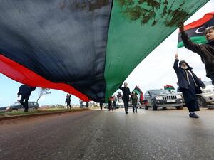 Libyans carry a giant national flag in the capital Tripoli during a celebration to mark the the upcoming eighth anniversary of the revolution which toppled strongman Moamer Kadhafi, on February 25, 2019. (AFP)