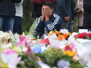 People pay their respects in front of floral tributes for victims of the March 15 mosque attacks, in Christchurch (AFP)