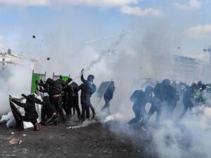 Yellow Vest protesters take shelter behind fences during clashes with riot police forces on the Champs-Elysees in Paris on March 16, 2019. (Alain JOCARD / AFP)