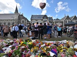 A group of students (C) sings in front of flowers left in tribute to victims at the Botanical Garden in Christchurch (AFP)