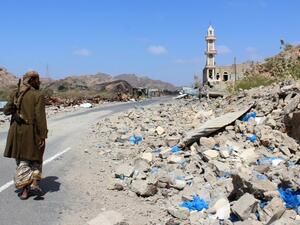 emeni fighter loyal to the government backed by the Saudi-led coalition walks past debris along a road near the town of Al-Shurayja in the southern Lahij province (AFP)