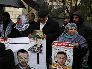 Supporters of hunger striking Palestinian prisoner Mohammed al-Qiq hold portraits as they demonstrate in solidarity with him on February 7, 2016, outside the offices of the International Committee of the Red Cross (ICRC) in the West Bank city of Ramallah. (AFP/Abbas Momani, File)