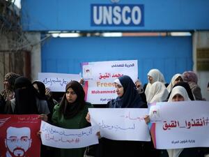 Palestinian women hold posters bearing a portrait of Palestinian hunger striking Palestinian journalist Mohammed al-Qiq on February 21, 2016. (AFP/Mahmud Hams)