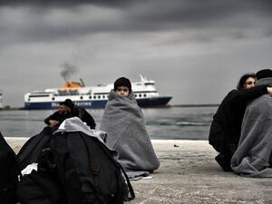 Children wrapped in covers stand in a harbour as migrants and refugees arrive on the Greek island of Lesbos while crossing the Aegean Sea from Turkey on March 2, 2016, in Mytilene. (AFP/Aris Messinis)