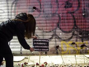 A woman puts a placard reading in Turkish "We are not afraid, we are here, we won't adjust" at the site of a blast on Istiklal Street, a major shopping and tourist district, in central Istanbul on March 19, 2016. (AFP/Bulent Kilic)