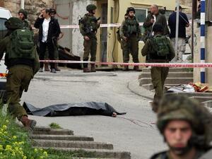 Israeli soldiers surround the body of one of the two Palestinians who were killed after wounding an Israeli soldier in a knife attack before being shot dead by troops in Hebron on March 24, 2016. (AFP/Hazem Bader)